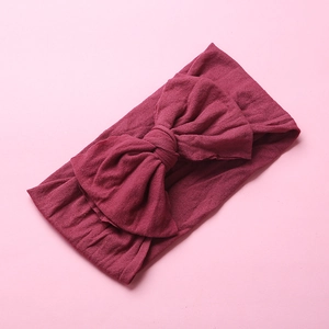Detail view of burgundy soft nylon headband featuring a large double-layered bow knot