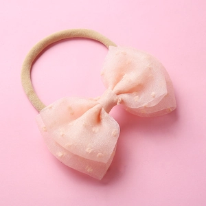 Détail du nœud en tulle rose avec pois texturés sur bandeau bébé en nylon sans couture