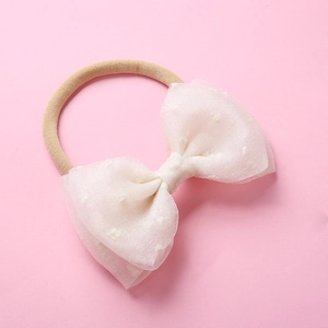 Détail d'un nœud en résille blanche à pois sur bandeau souple en nylon pour bébés