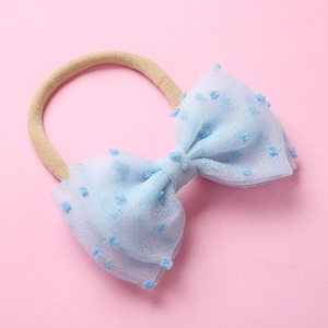 Détail du nœud en tulle à pois sur un bandeau en nylon souple pour nouveau-né