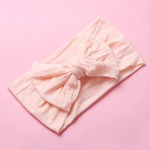 Detail of soft pale pink nylon baby headband with a large handmade bow knot