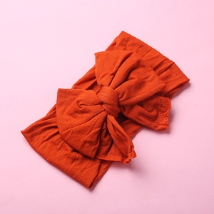Detailed texture of burnt orange nylon baby headband with oversized swallowtail bow
