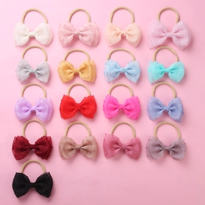 Vue à plat de 17 bandeaux bébé colorés en nylon avec des nœuds en résille à pois