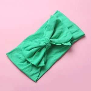 Close-up detail of soft grass green nylon bow headband with elastic knit texture