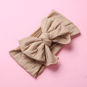 Detail of soft nylon baby headband with large swallowtail bow in nude color texture