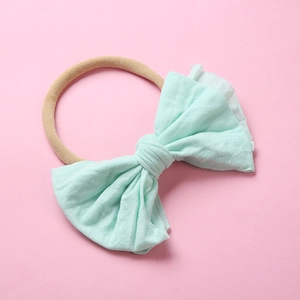 Détail du bandeau avec nœud bleu clair pour bébé en lin sur fond rose uni