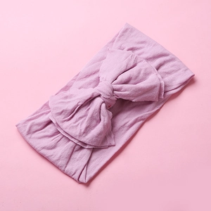 Detail of soft nylon baby headband showing double-layered large bow on pink background