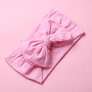 Detail shot of a soft pink nylon baby headband with a large decorative double bow