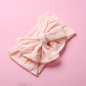 Detail of soft pale pink nylon baby headband with a multi-layered large bow texture