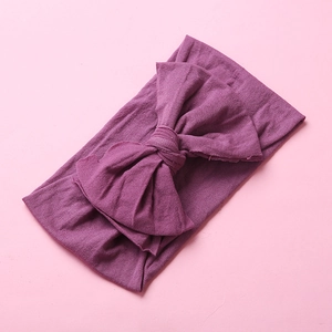 Detail of soft purple nylon baby headband with large bow knot on pink background