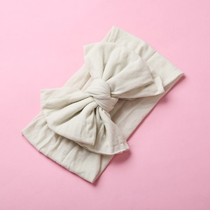 Close-up of cream nylon bow headband showing soft ribbed texture and handcrafted knot
