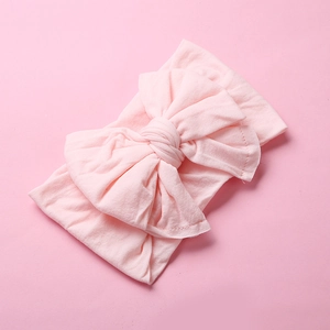 Detail of the soft knit fabric texture and double-layered knot on the light pink baby headband