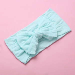 Detail of soft mint green nylon baby headband with a large knotted decorative bow