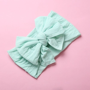 Detail of mint green soft nylon baby headband with a large layered knot bow