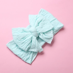 Detail of soft mint green nylon baby headband featuring a large double-layered bow knot