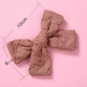 Gros plan détaillé d'une barrette à nœud en coton brodé avec motif floral rose