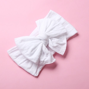 Close-up of soft white nylon baby headband featuring a large double-layered bow detail