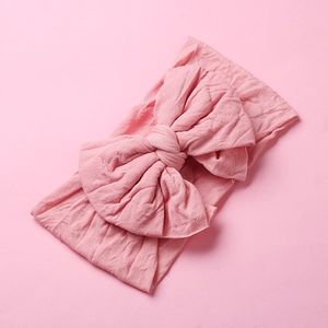 Detail shot of baby headband featuring soft pink nylon fabric and handmade butterfly bow