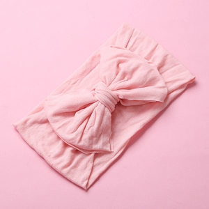 Detail of soft nylon baby headband with a large bow in light pink knit fabric