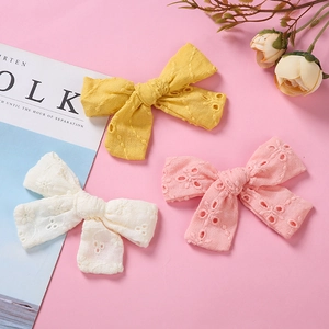 Trois barrettes papillon en dentelle brodée blanc rose et jaune sur fond rose