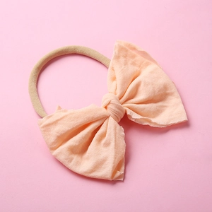 Détail du nœud rose pêche sur un bandeau en nylon souple pour bébés et nourrissons
