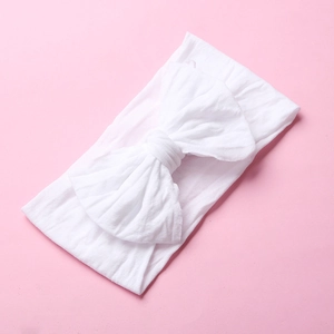 Detailed texture of white soft nylon bow headband for baby girls on pink background