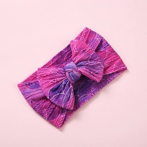 Détail d'un bandeau bébé en nylon avec nœud floral violet et texture en maille torsadée