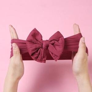 Macro shot showing high elasticity of the soft nylon baby bow headband in wine red