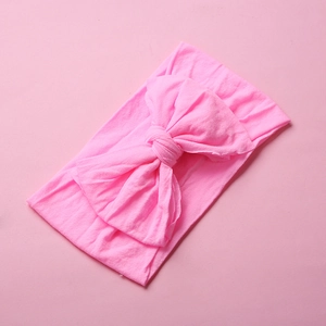 Close-up of soft pink nylon baby headband with large decorative hand-tied bow detail