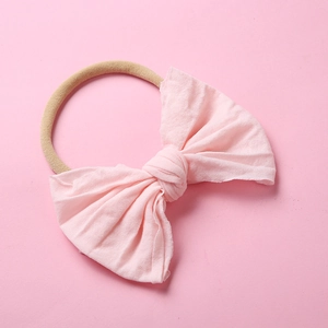 Détail d'un bandeau en nylon rose pour bébé avec un grand nœud papillon texturé