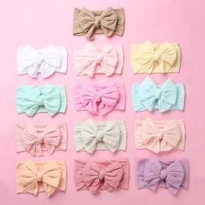 Flat lay of 13 colorful soft nylon elastic headbands with oversized bows for infants