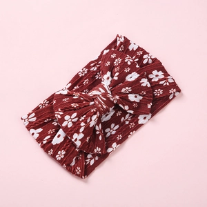 Détail d'un bandeau bébé en nylon côtelé avec motif floral rouge et nœud papillon