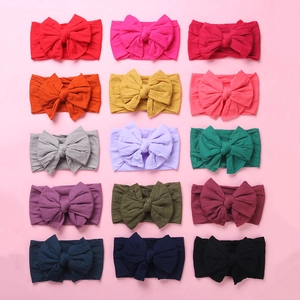 Flat lay of 15 colorful nylon baby bow headbands in various vibrant shades and patterns