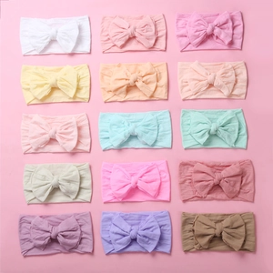 Flat lay of soft nylon baby headbands with large bows in 15 different pastel colors