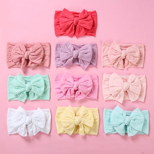 Flat lay of soft nylon baby headbands with large double layer swallowtail bows in 10 colors