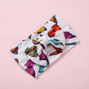 Détail du bandeau bébé en maille torsadée avec motifs papillons et grand noeud pap