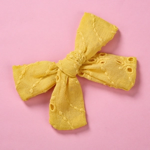 Gros plan détaillé sur la broderie en dentelle jaune d'un nœud pour barrette enfant