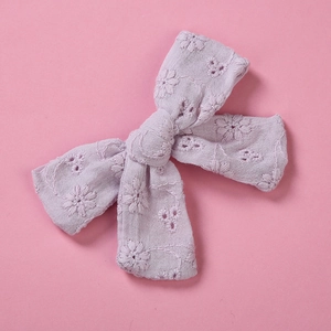 Détail d'une pince à cheveux en coton lavande avec broderie florale et design ajouré