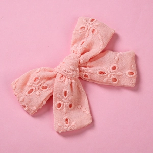 Détail de la pince à cheveux noeud rose avec broderie florale ajourée en coton doux