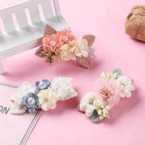 Three pieces of simulated flower hair clips with pearls for girls on a soft pink background