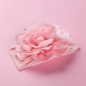 Detail of pink nylon baby headband featuring a large multi-layered 3D fabric flower