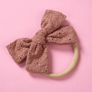 Detail of baby headband featuring dusty pink cotton bow with floral embroidery