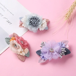 Detailed view of handmade chiffon flower hair clips with pearls on a pink background