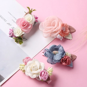 Close-up of four handmade floral hair clips for girls with fabric petals and pearls