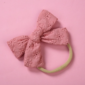 Detail showing pink cotton bow with floral embroidery on soft elastic nylon headband