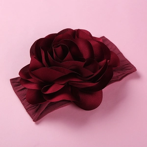 Close-up of deep burgundy fabric rose headband for babies with soft nylon elastic texture