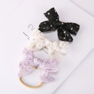 Détail de trois bandeaux en maille avec nœuds et broderie marguerite en noir, blanc et lilas