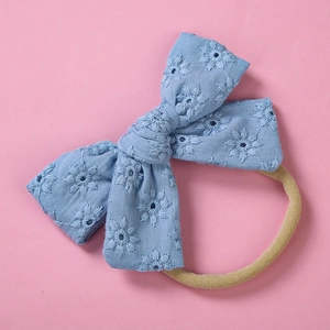 Close-up of baby headband featuring blue embroidered floral bow and soft nylon band