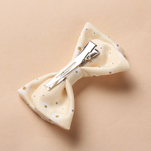 Détail d'une pince nœud pour bébé en tissu jaune floral avec clip crocodile en métal