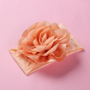 Detail of soft nylon infant headband with a large layered 3D chiffon flower in peach pink